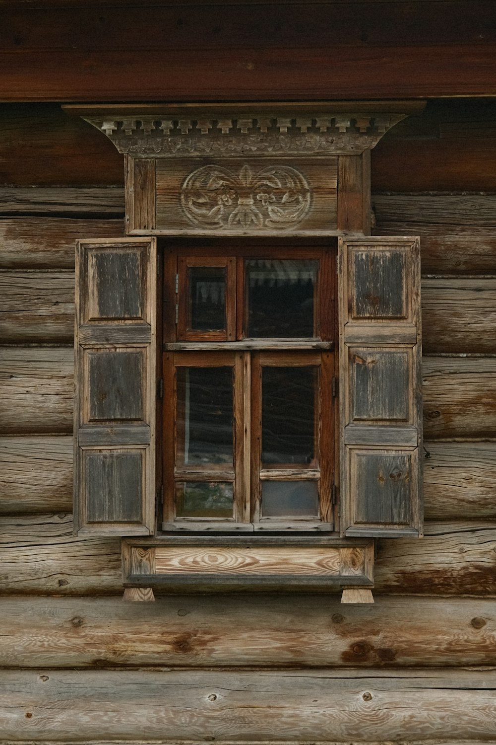 a window with wooden shutters on a log cabin