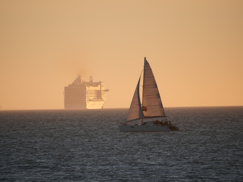 a sailboat and a cruise ship in the distance