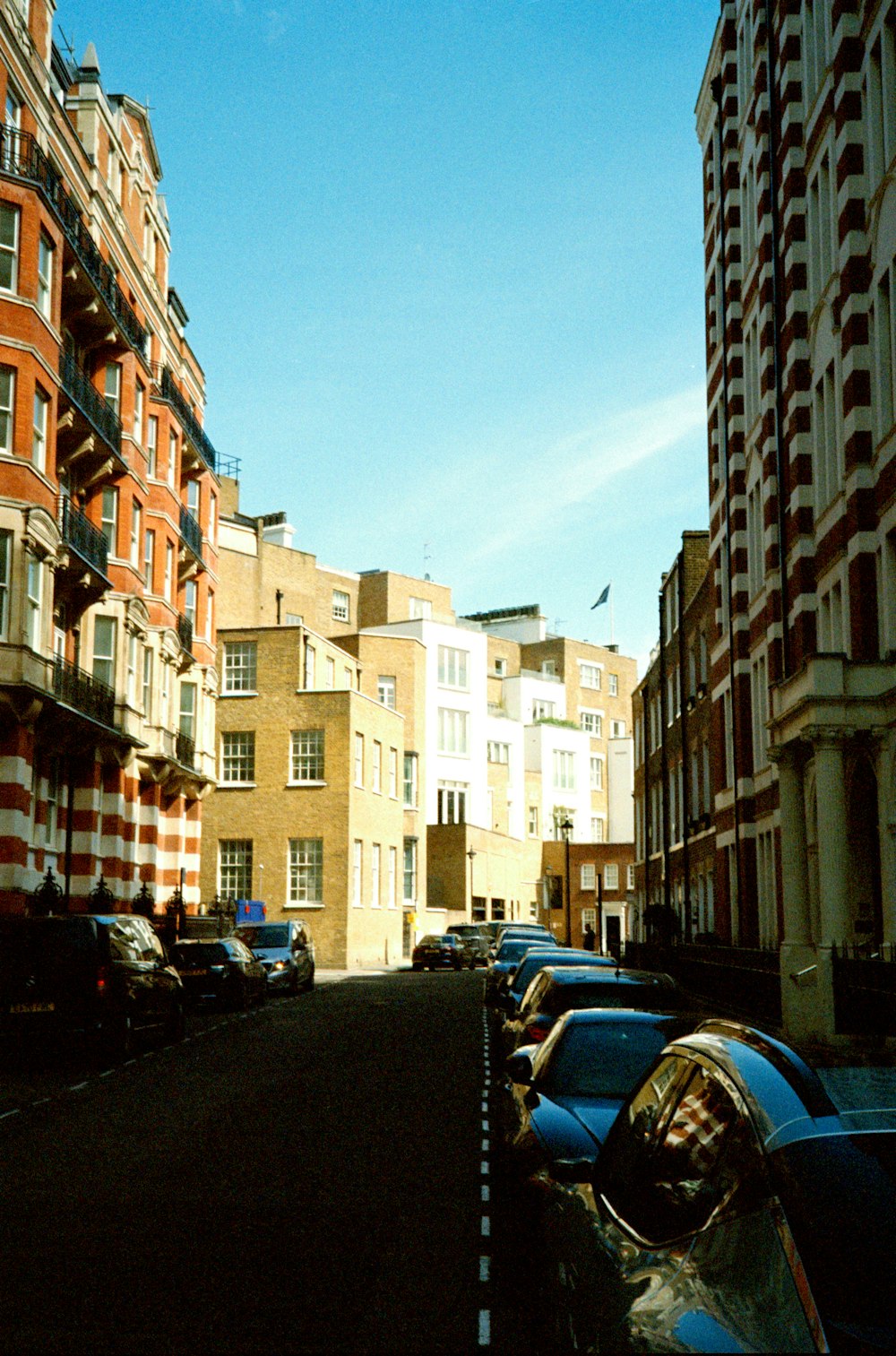 a city street lined with tall buildings and parked cars