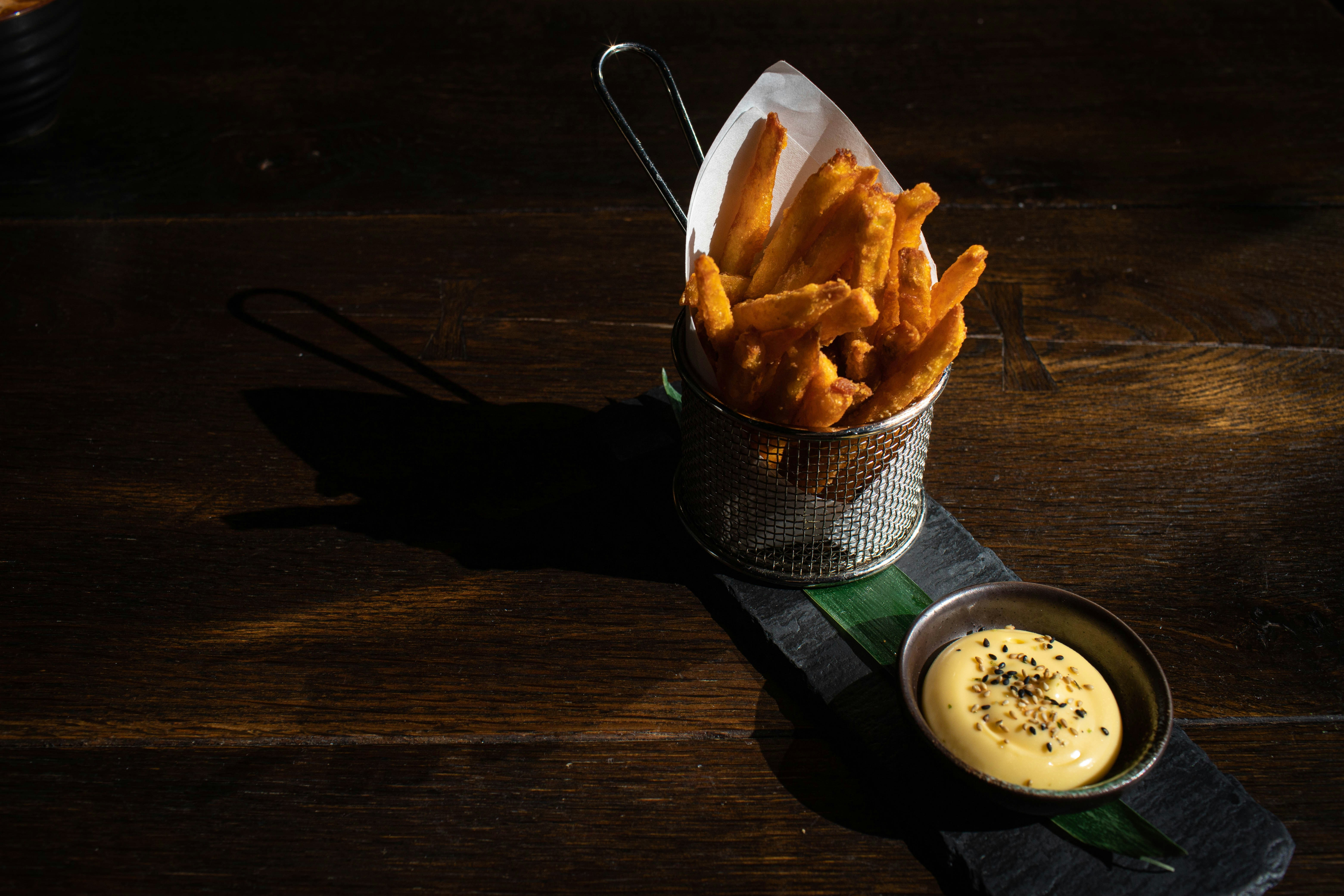 Ein Korb mit Pommes Frites neben einer Schüssel Dip