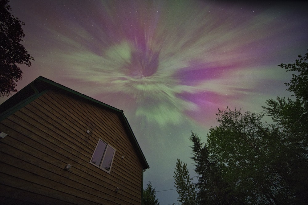 a house with a purple and green aurora bore in the sky