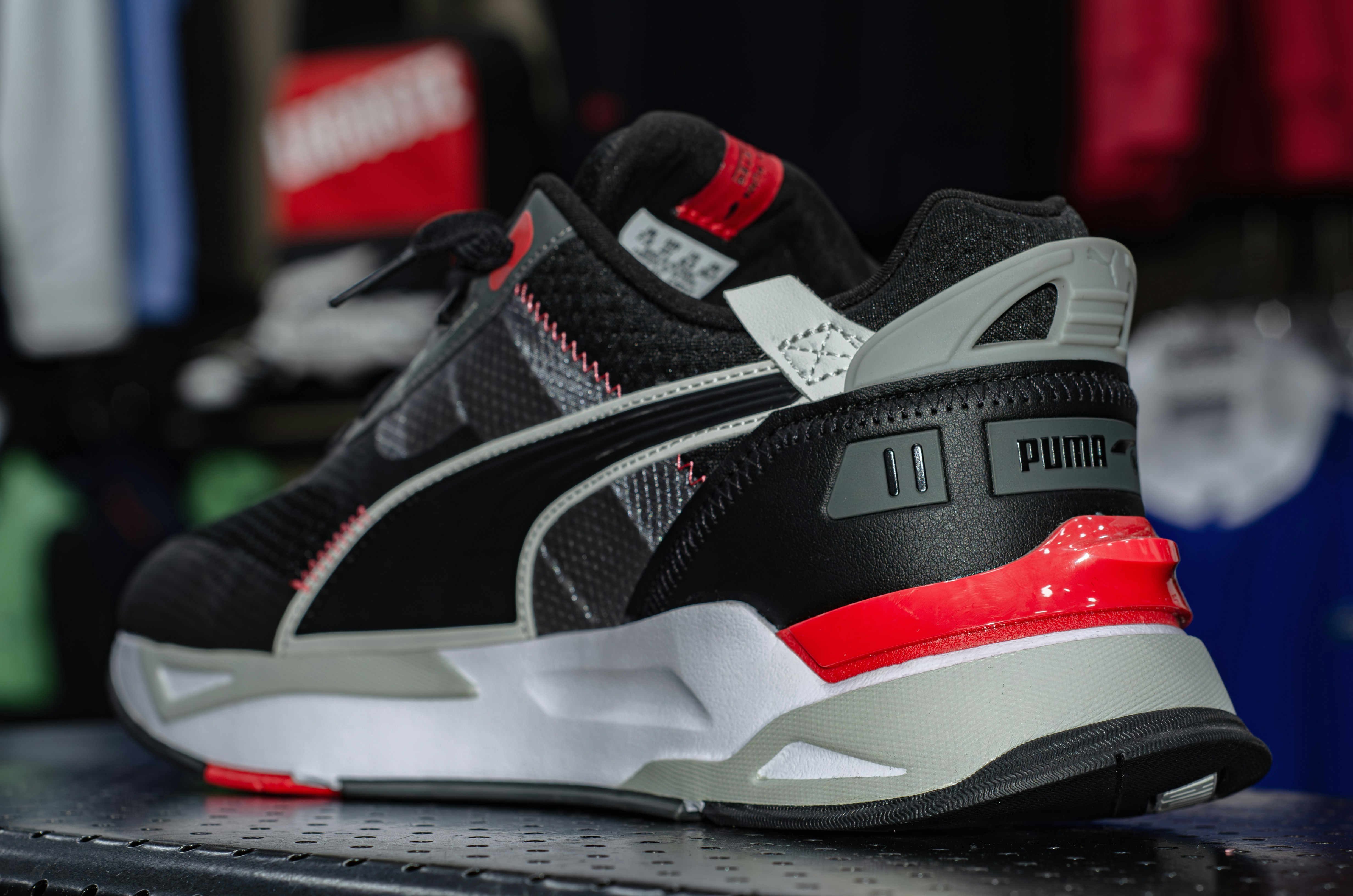 un gros plan d’une chaussure noire et rouge sur une étagère