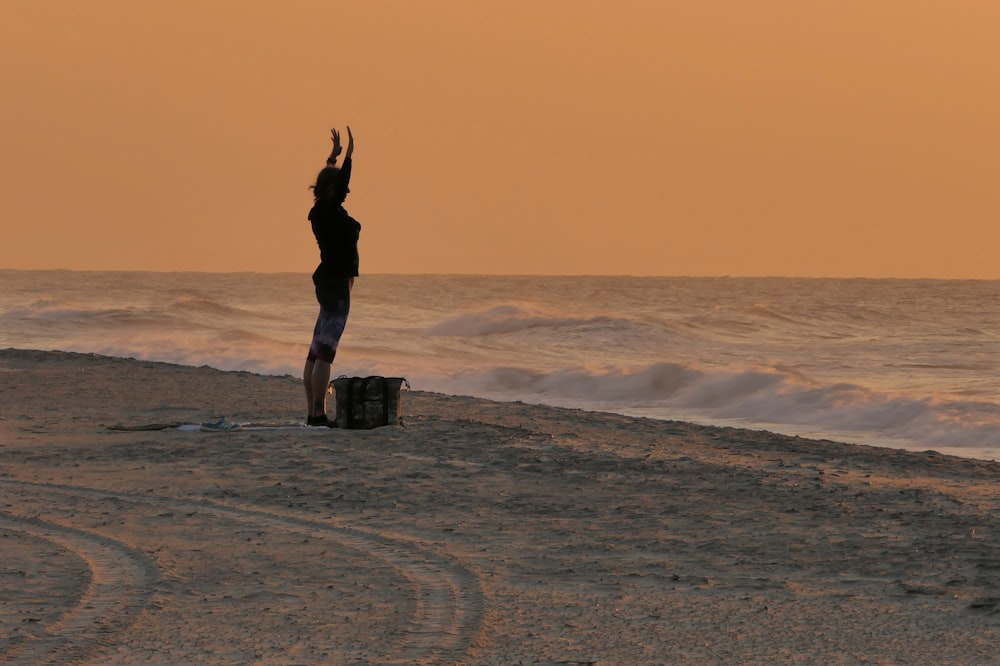 a person standing on a beach with their arms in the air