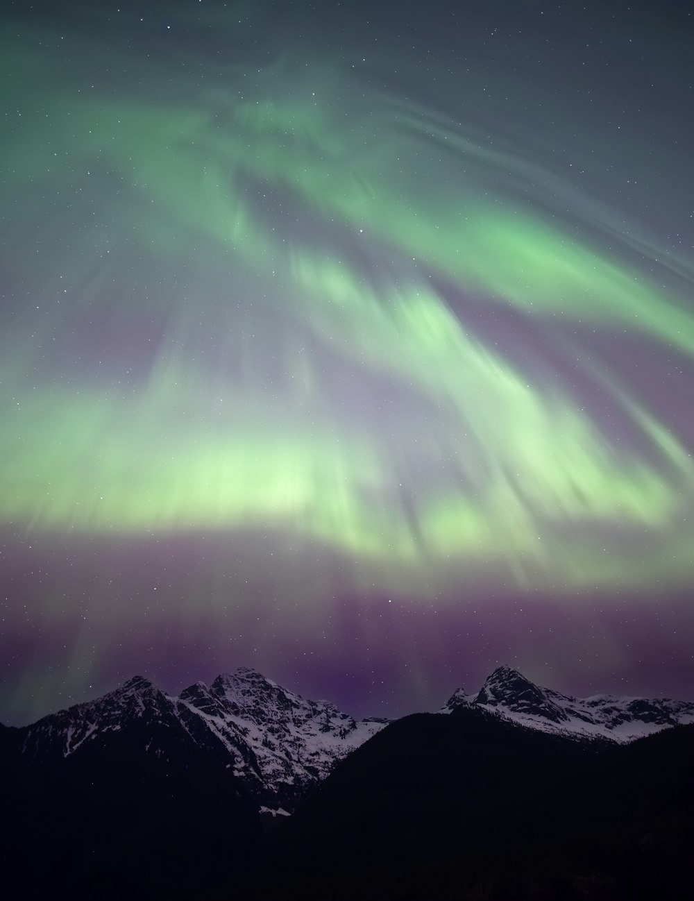 a green and purple aurora bore over a mountain range