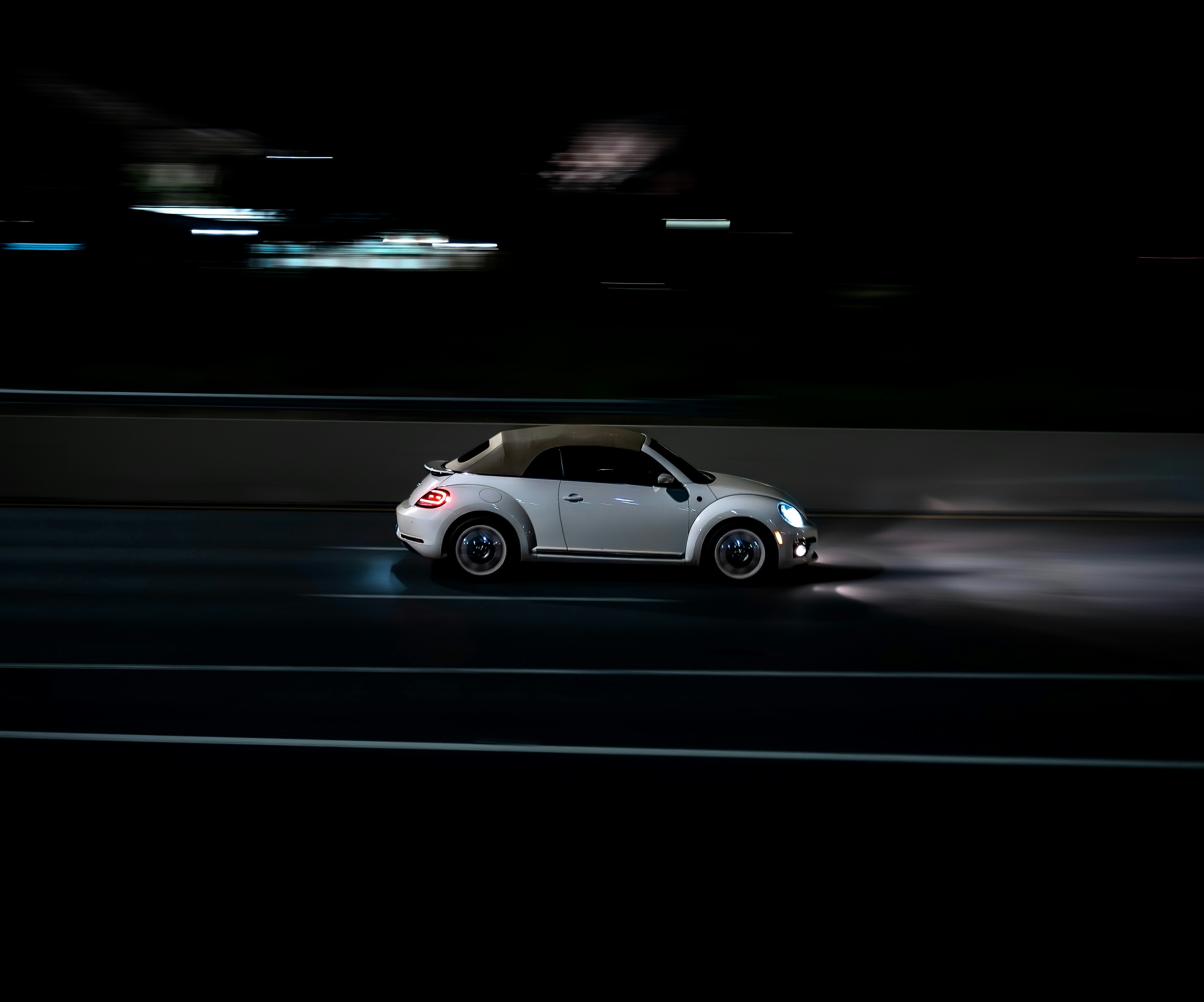 A small white car driving down a street at night photo – Free Car Image ...