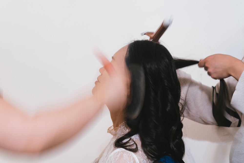 a woman is cutting another woman's hair with scissors