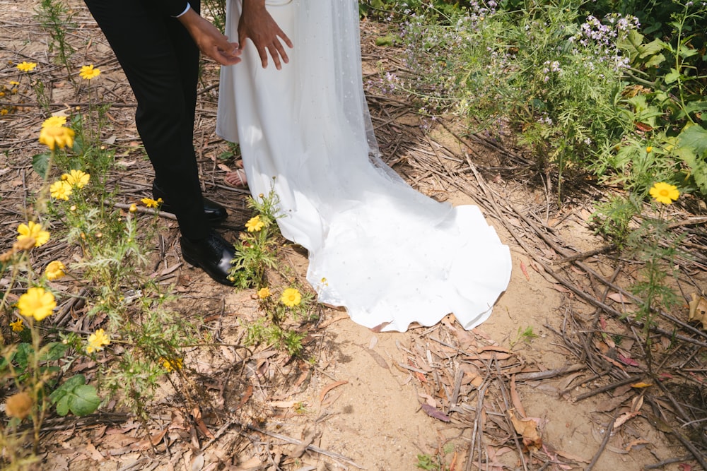 a bride and groom standing in a field of wildflowers