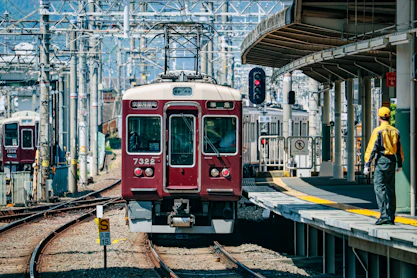 a red train traveling down train tracks next to a train station