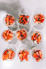 a group of small glass bowls filled with sliced strawberries