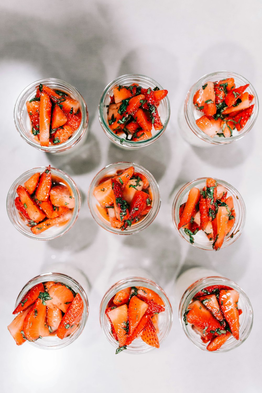 a group of small glass bowls filled with sliced strawberries
