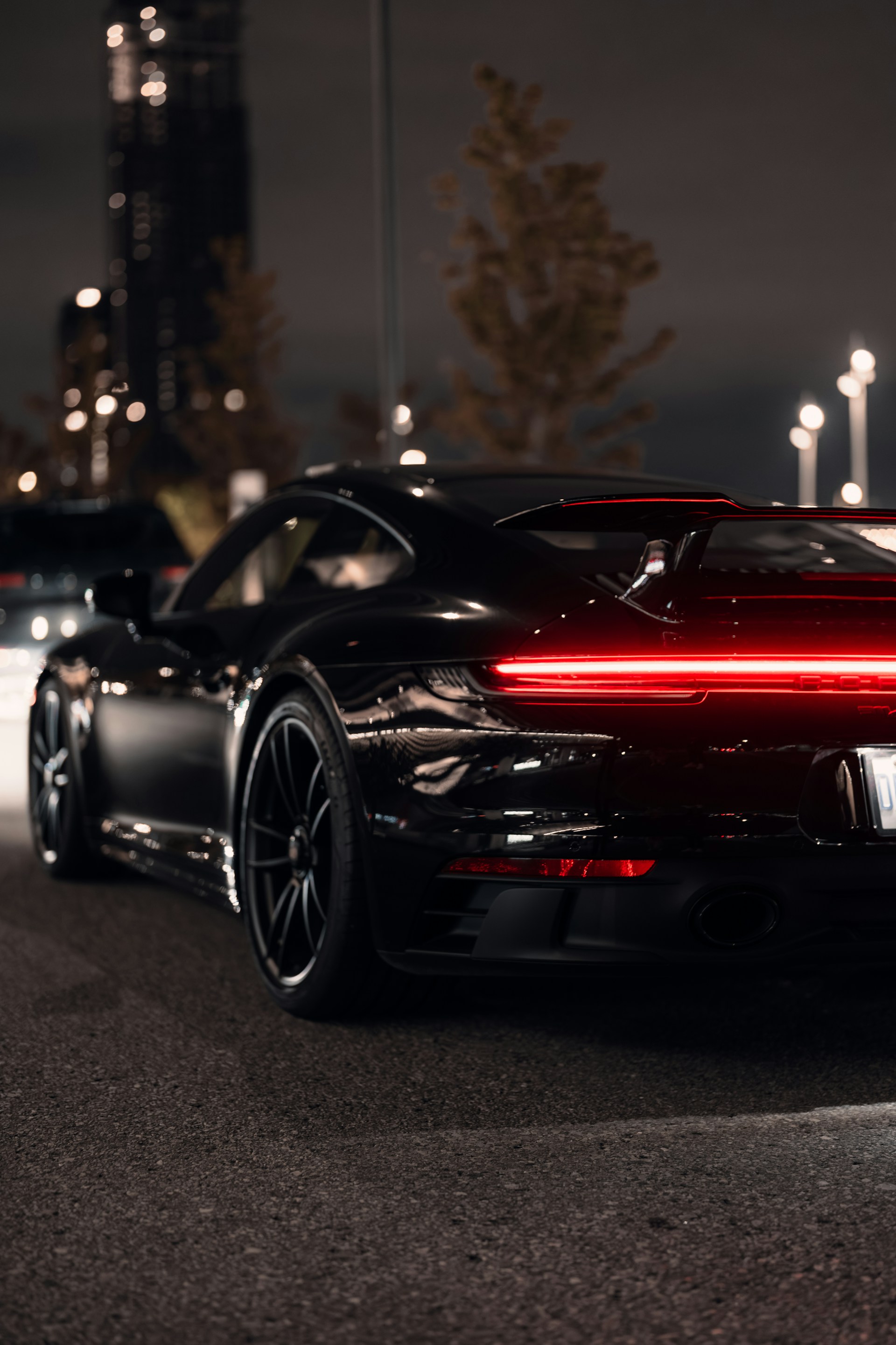 a black sports car driving down a street at night