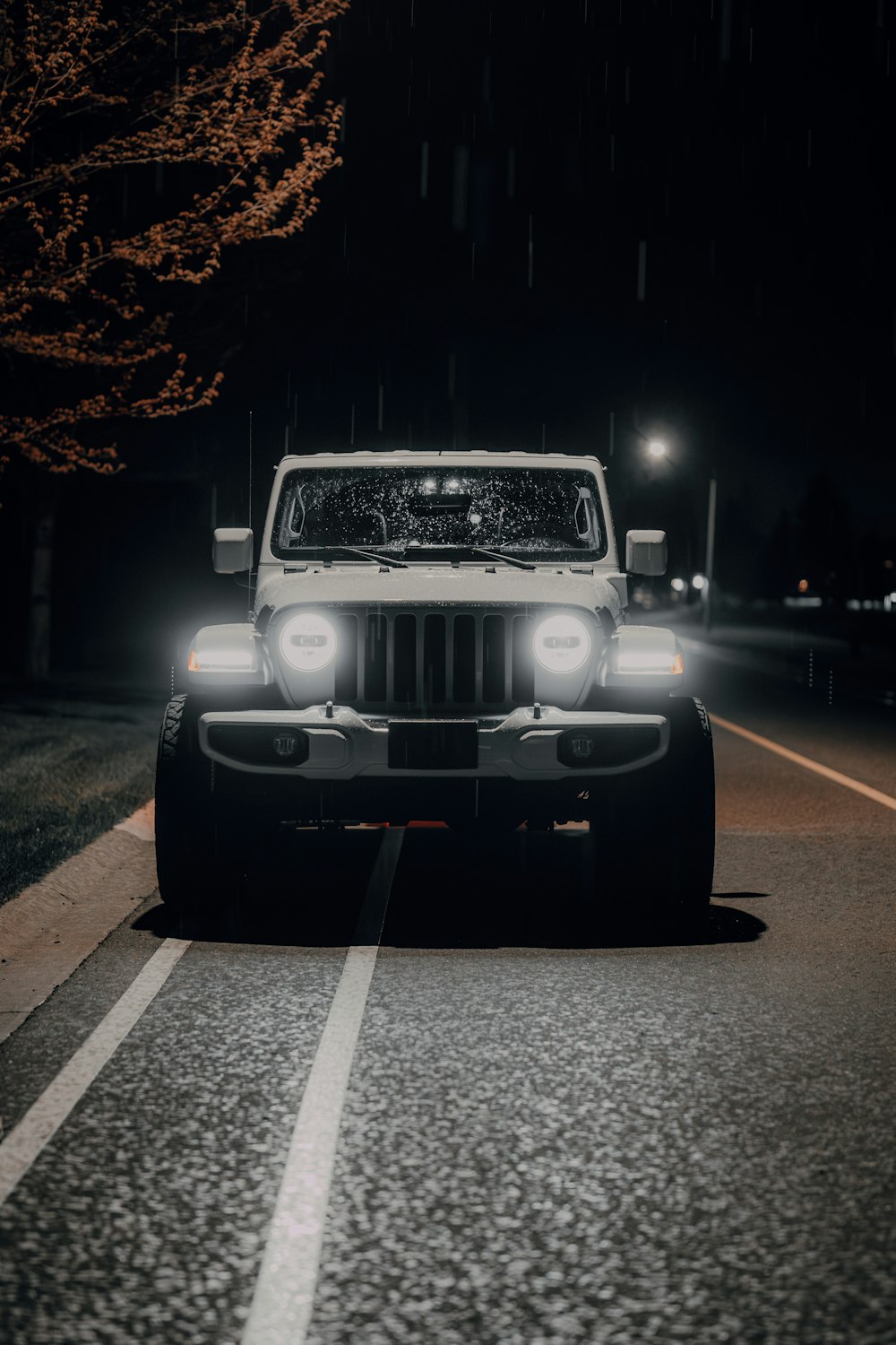 a white jeep driving down a street at night