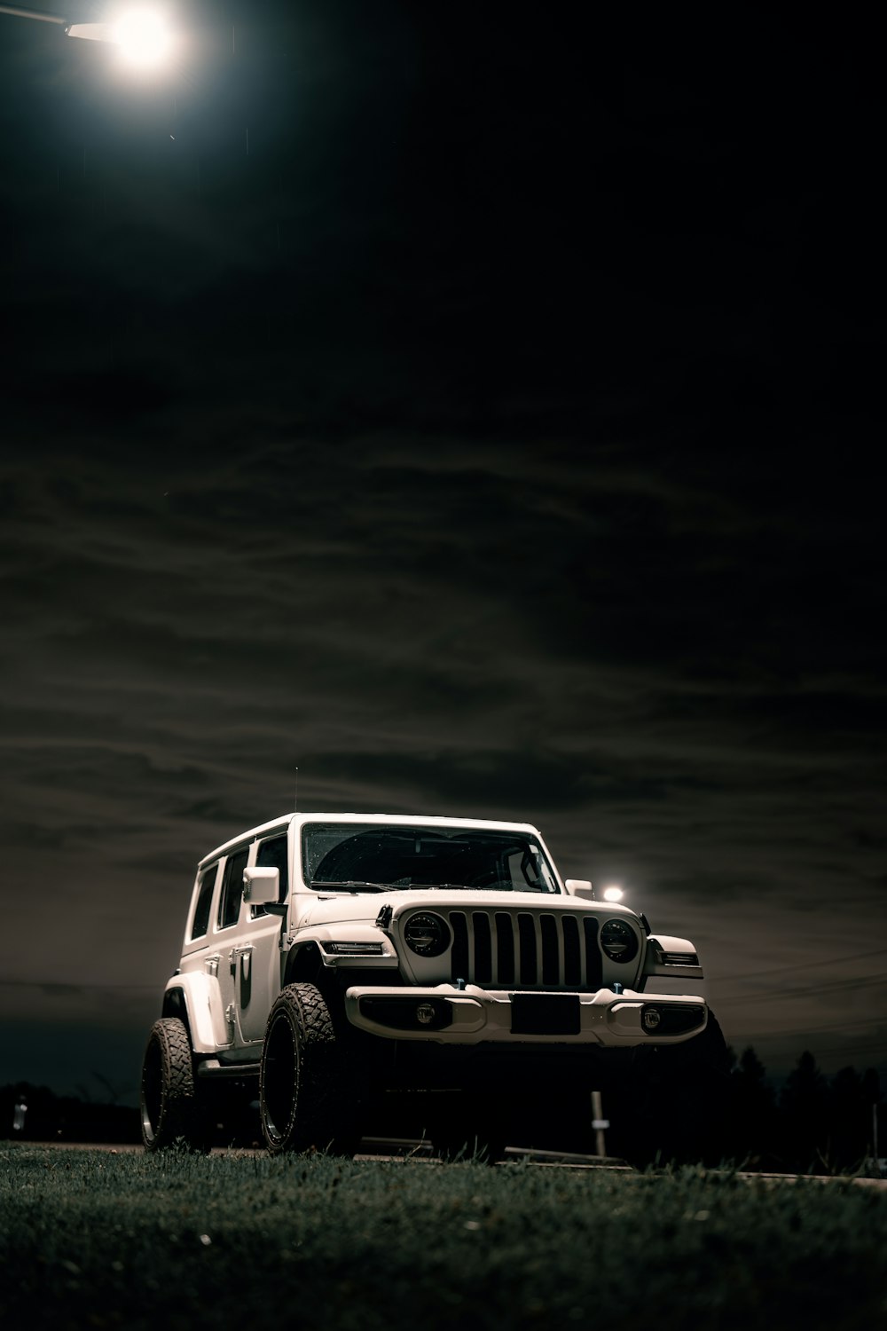 a jeep parked in a field under a full moon