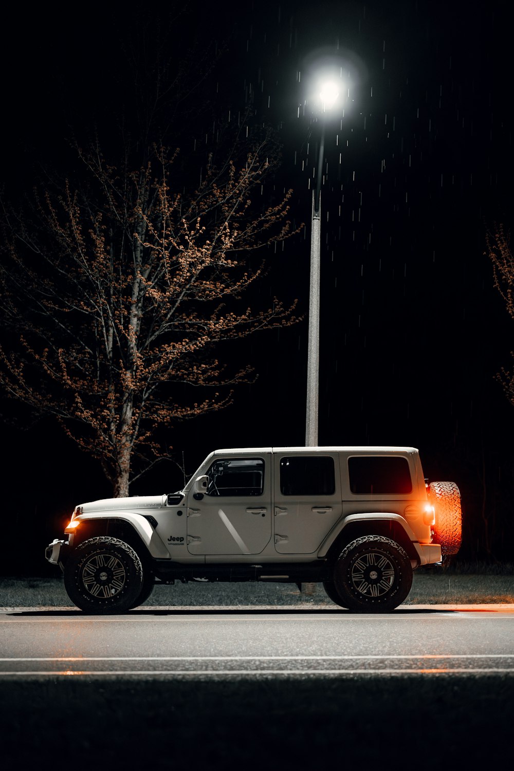 a white jeep parked on the side of the road at night