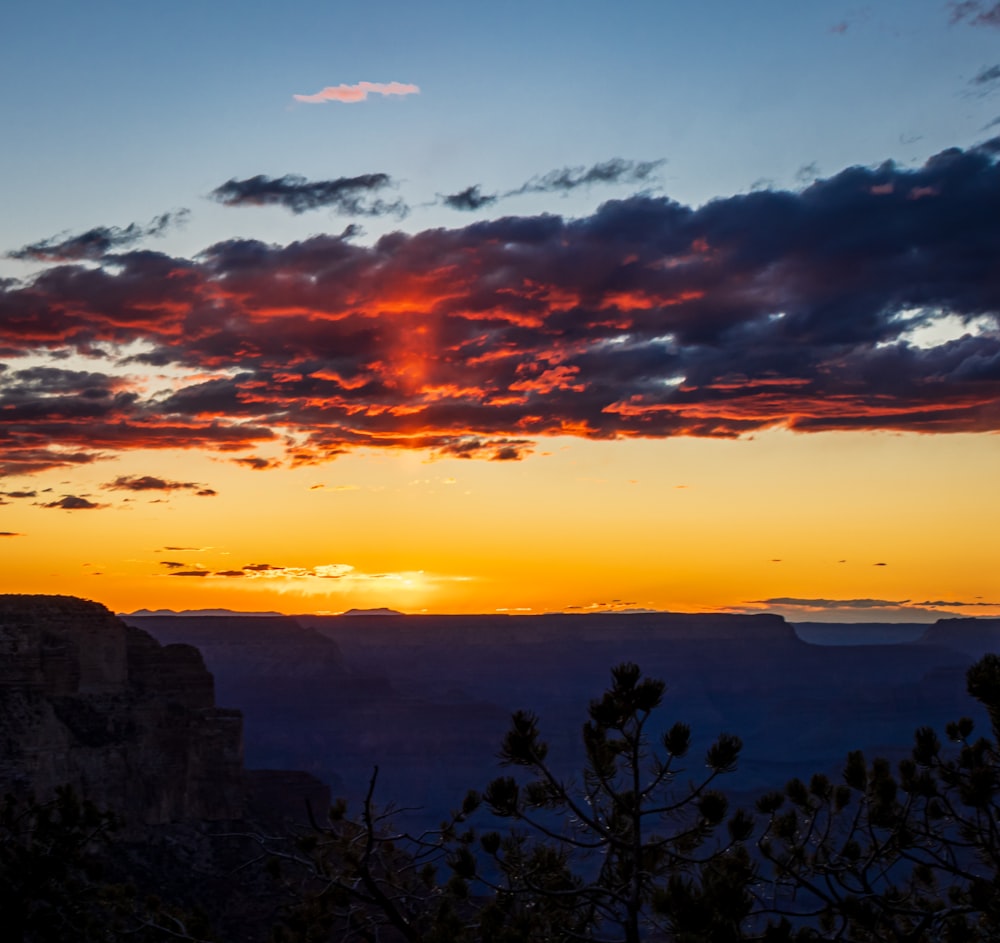 the sun is setting over a canyon with a mountain in the background