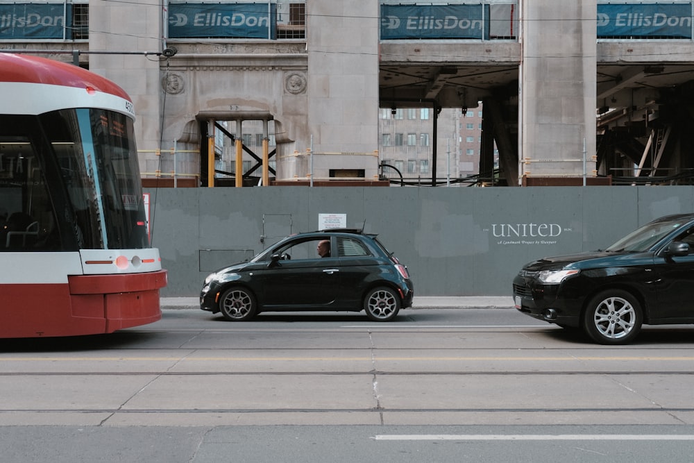 a red and white car and a black car on a street