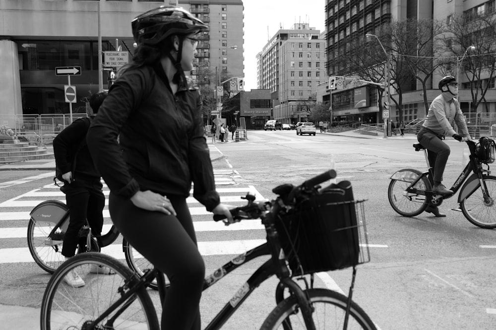 a woman riding a bike down a street next to a man riding a bike