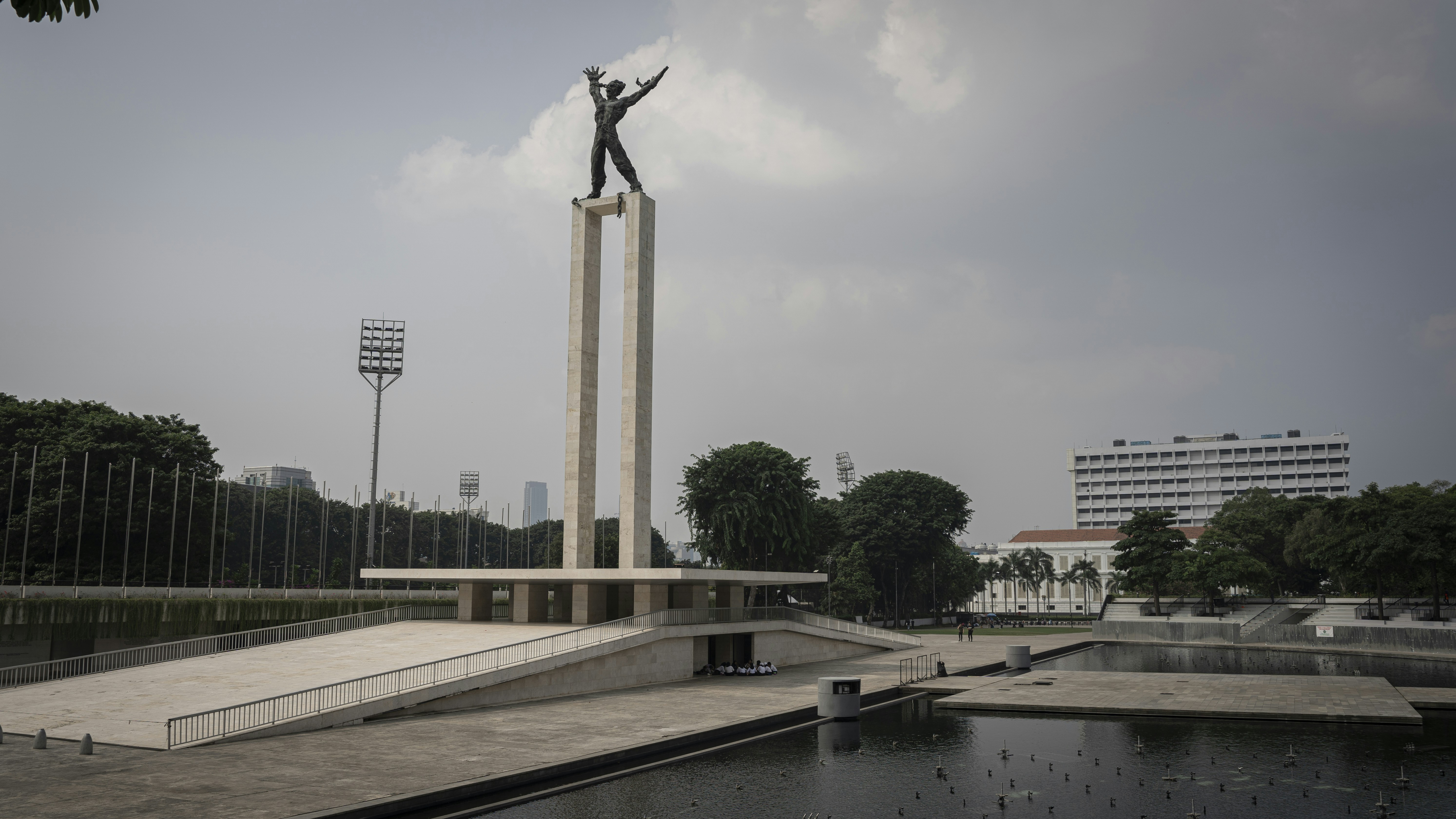 a statue of a man standing on top of a tall pole