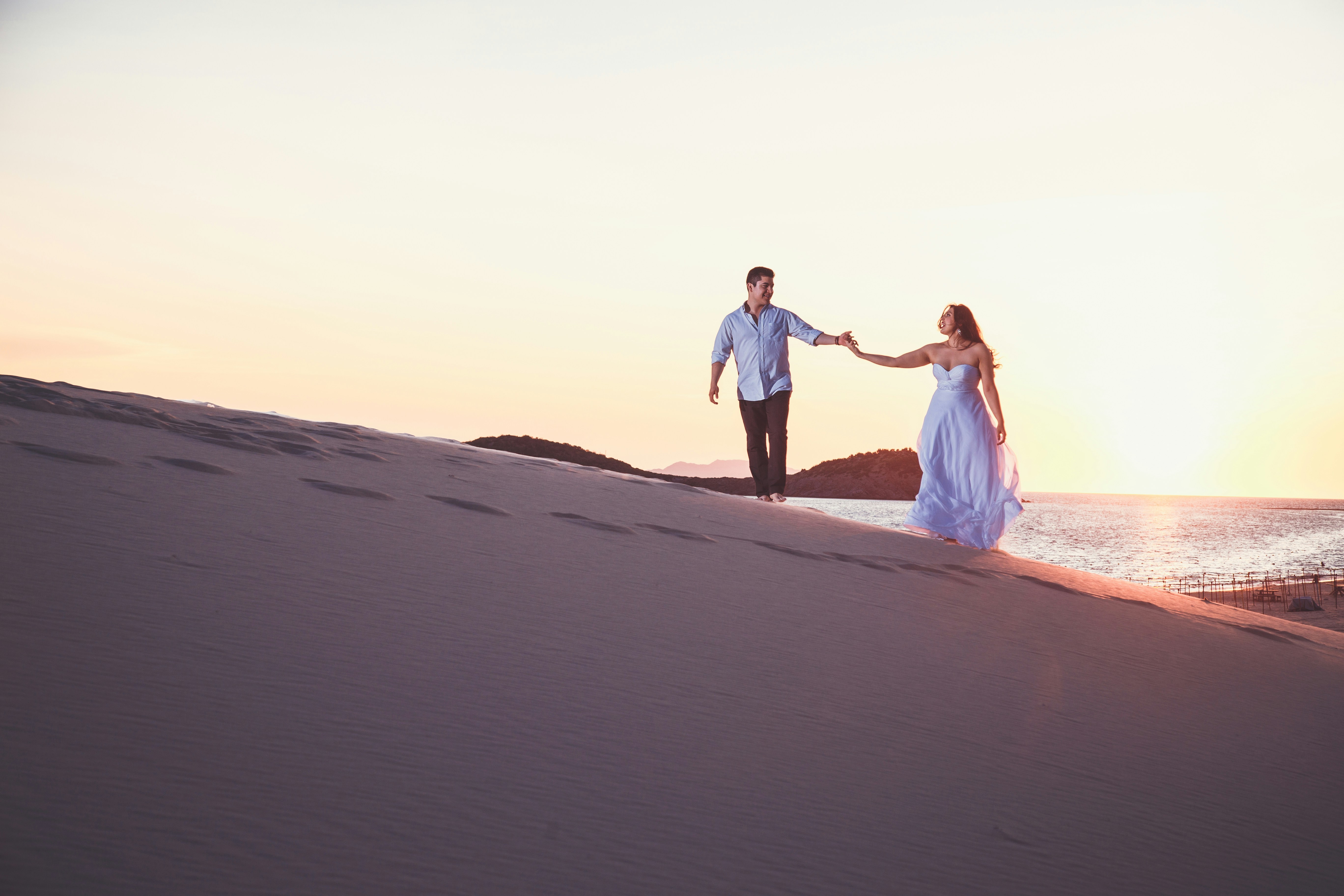 a man and a woman holding hands on a beach