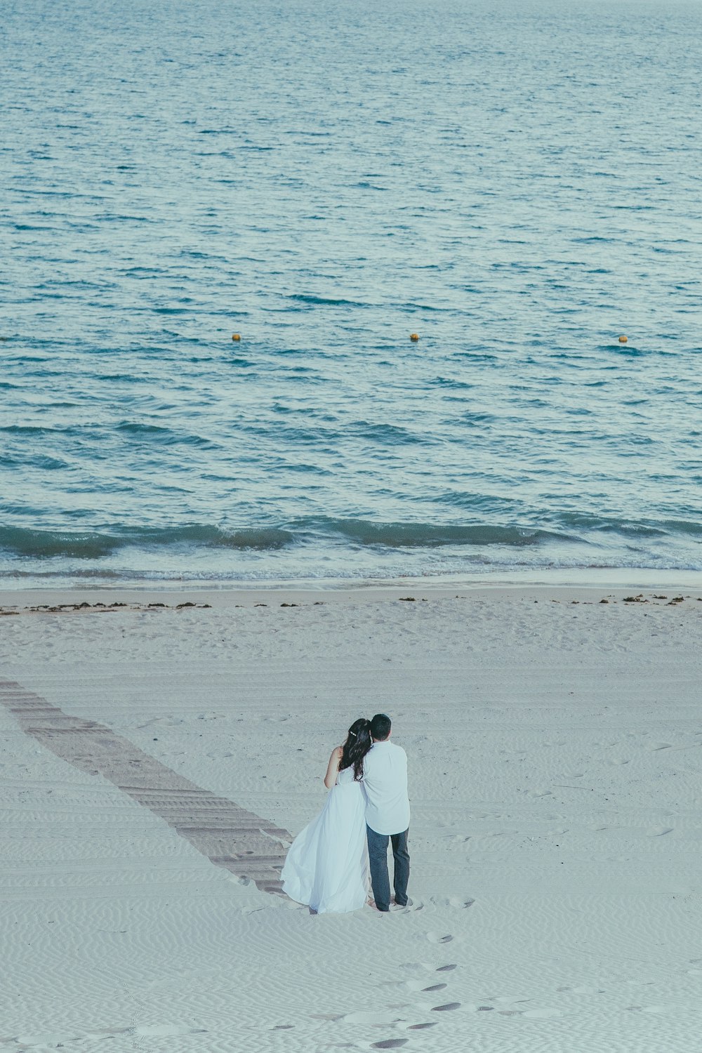 a man and a woman standing on a beach next to the ocean