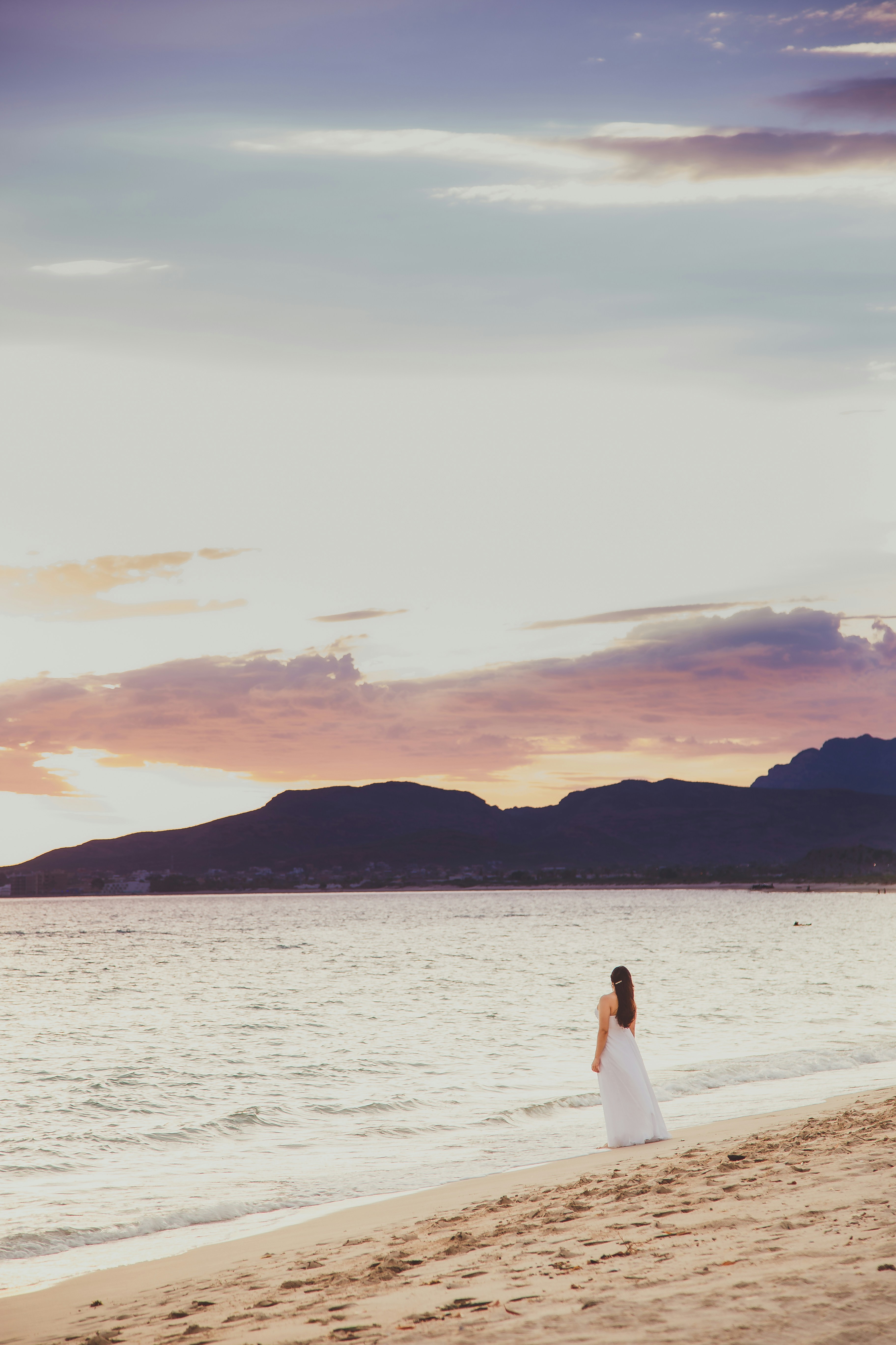 a woman standing on top of a beach next to the ocean