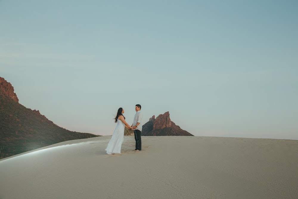a man and a woman standing on top of a desert