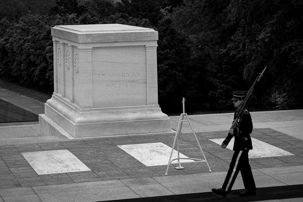 un homme en uniforme passant devant un monument