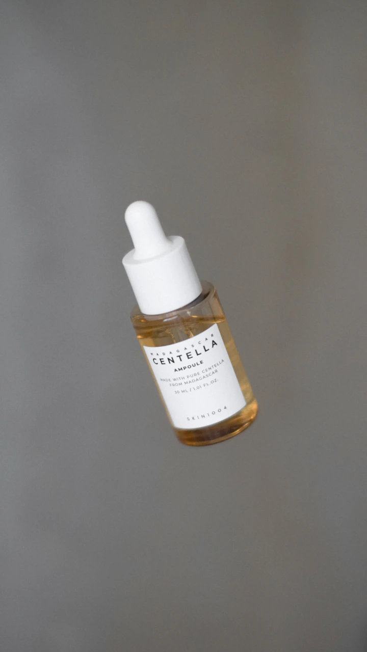 Glass dropper bottle with a single drop of serum suspended at the pipette tip