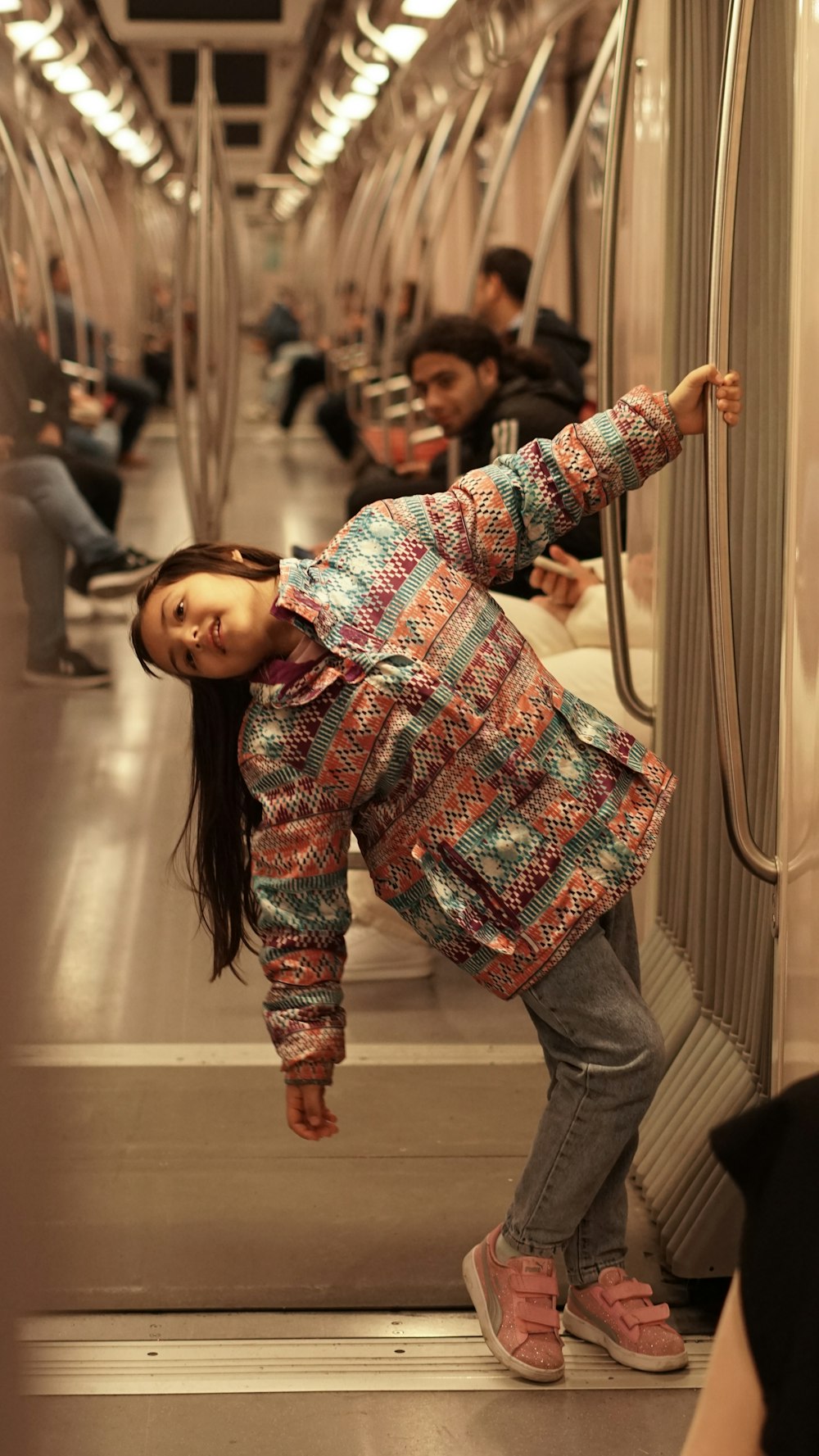a young girl standing on a subway train