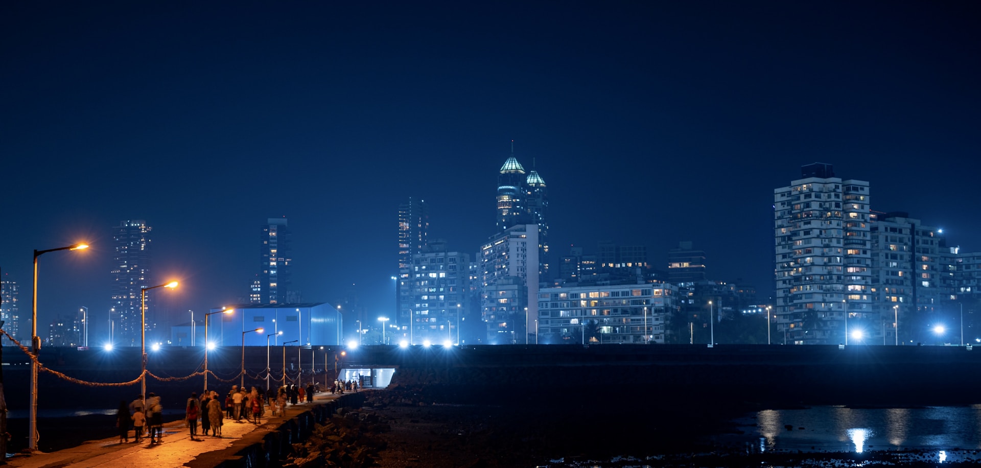 a group of people walking down a sidewalk at night