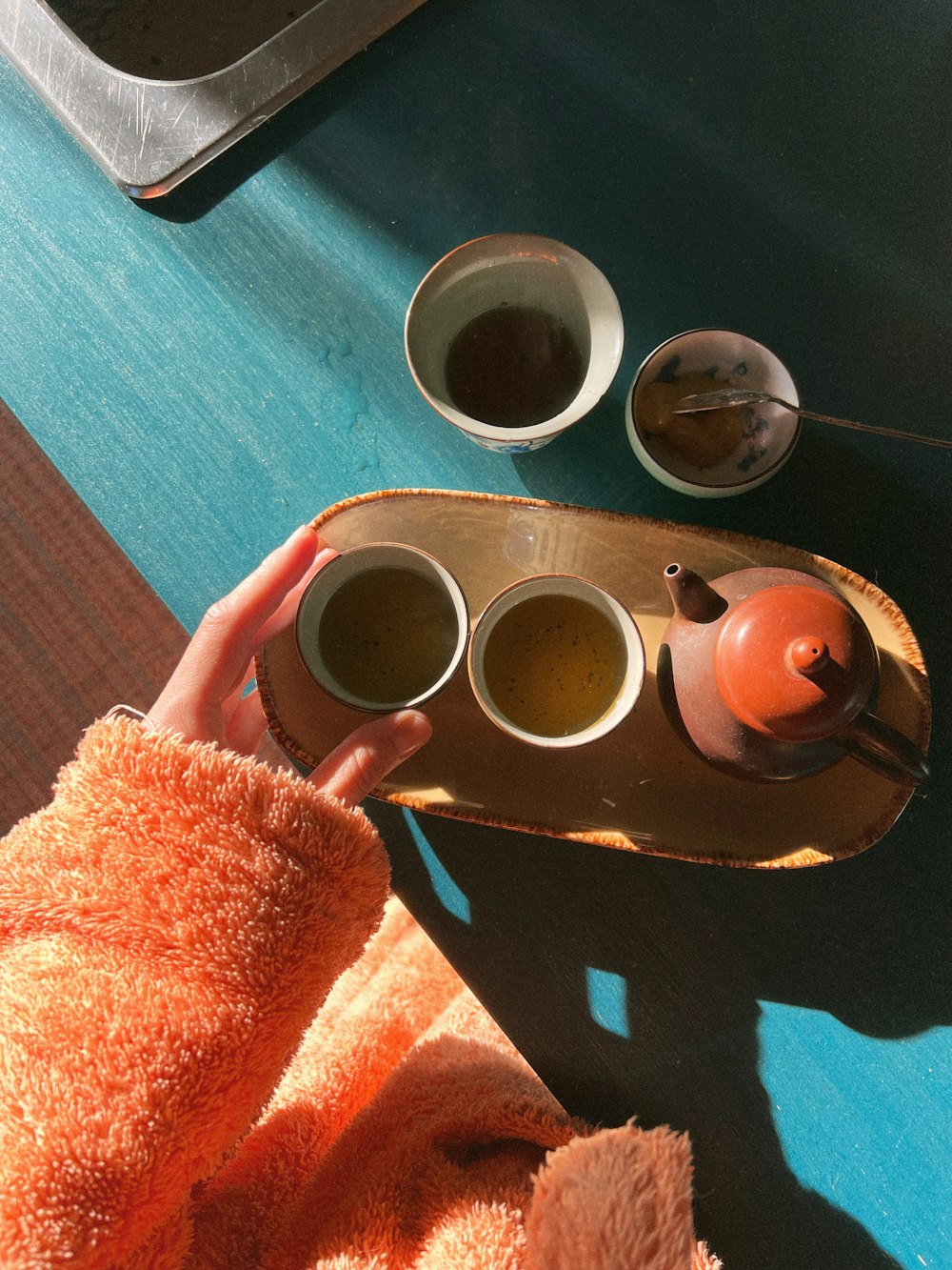 a person is holding a tray with three cups of tea