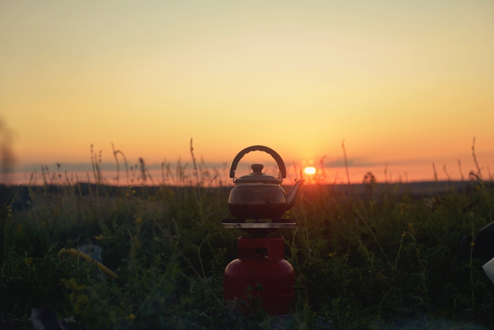 a tea kettle sitting on top of a red fire hydrant