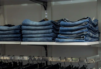 a bunch of jeans are stacked on a shelf