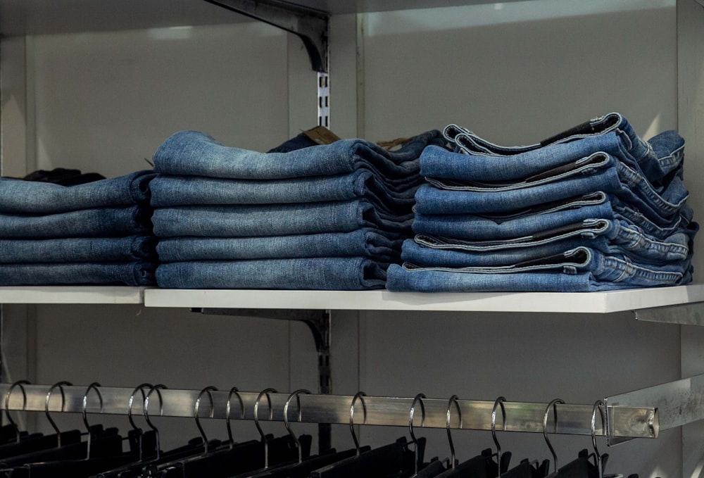 a bunch of jeans are stacked on a shelf