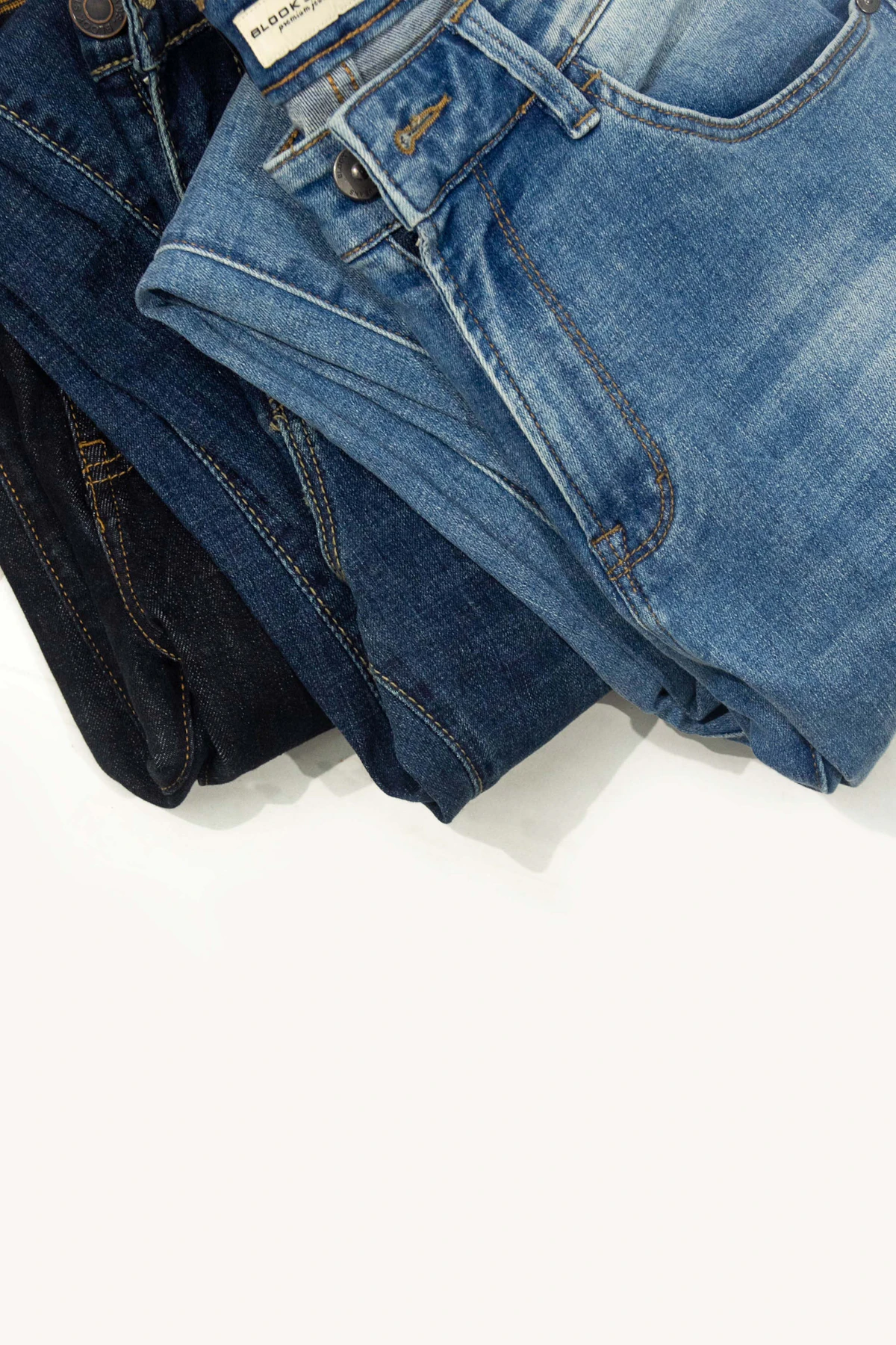 Três calças jeans masculinas dobradas em tons de azul e preto