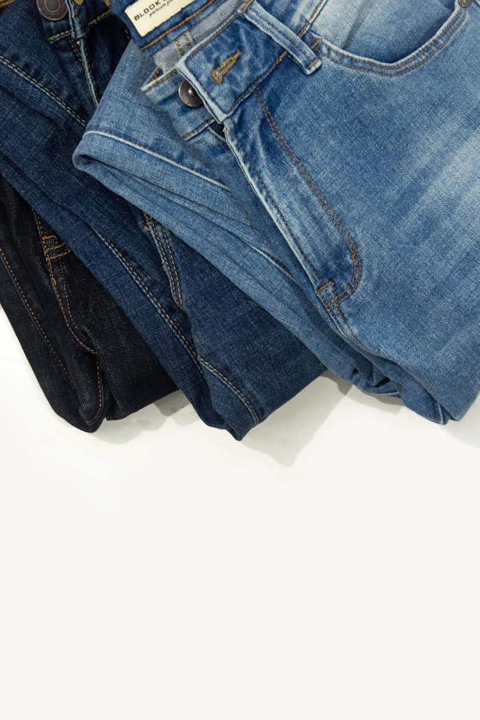Três calças jeans masculinas dobradas em tons de azul e preto