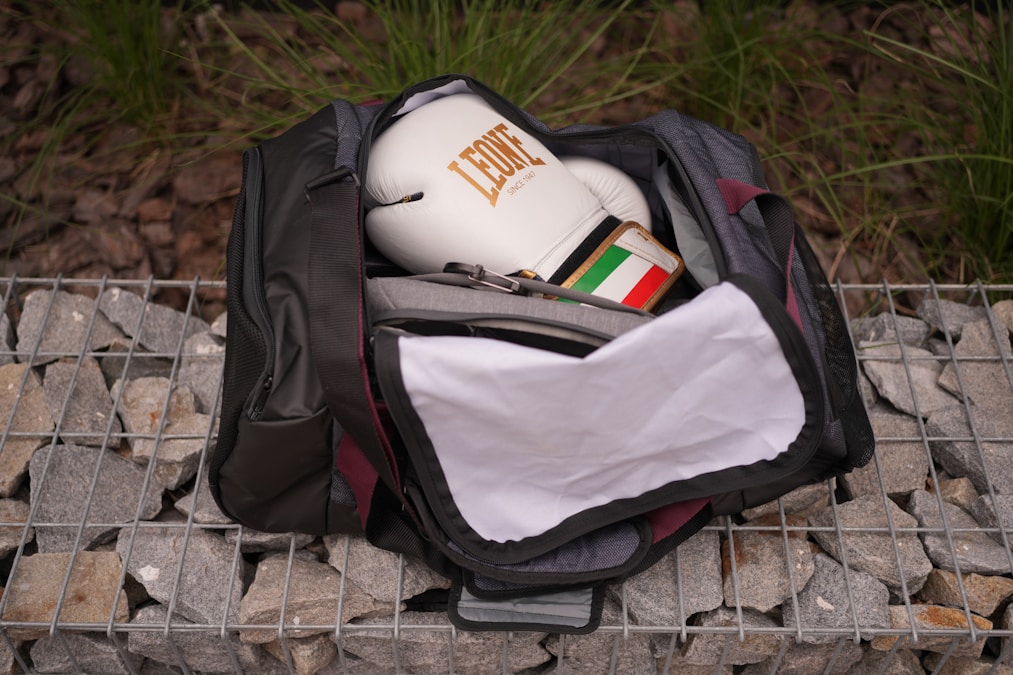 Open gym bag packed with boxing gloves, a towel and a water bottle