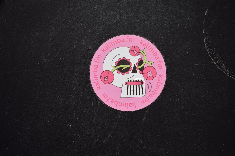 a pink sticker with a skull and flowers on it