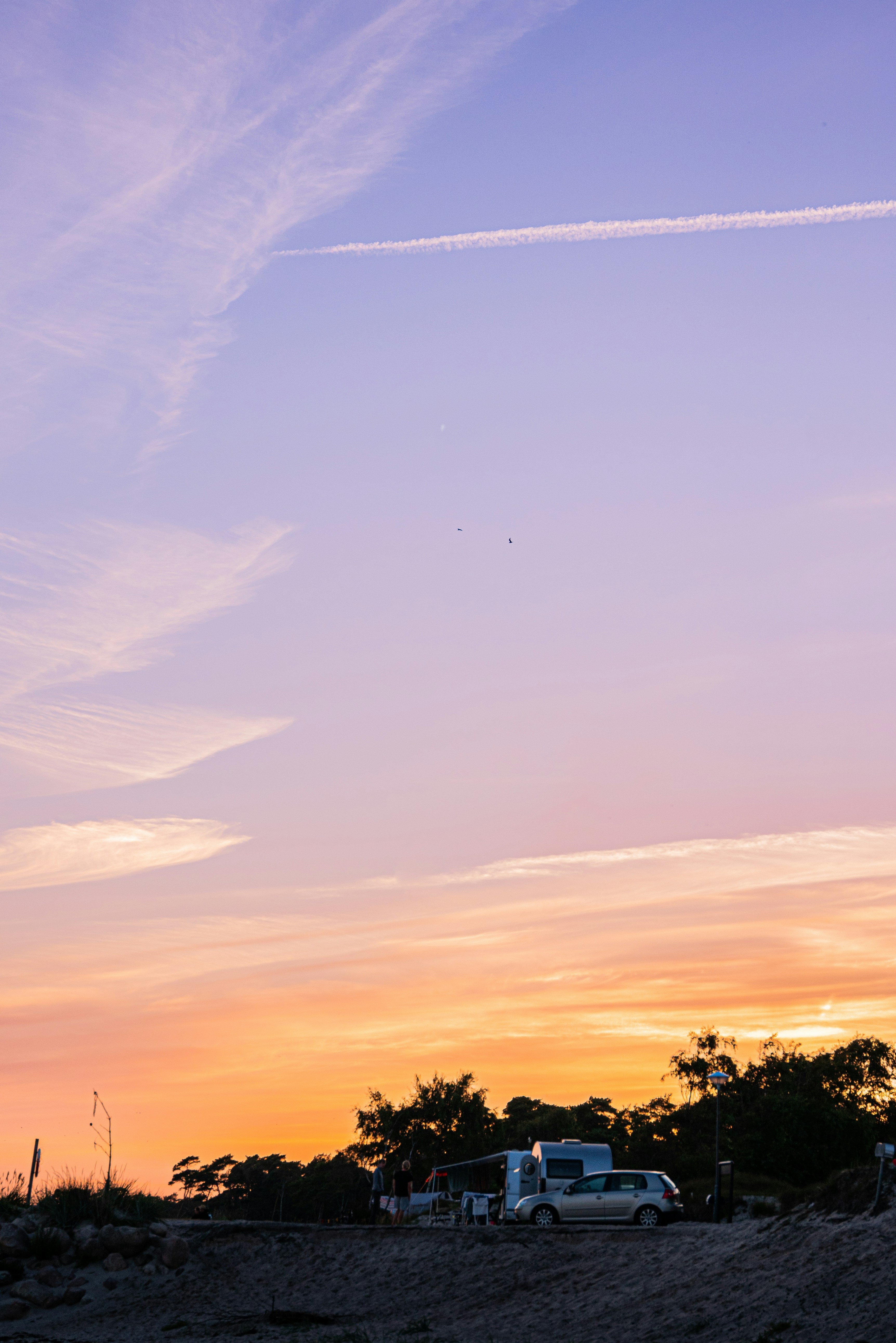 a plane flying in the sky at sunset