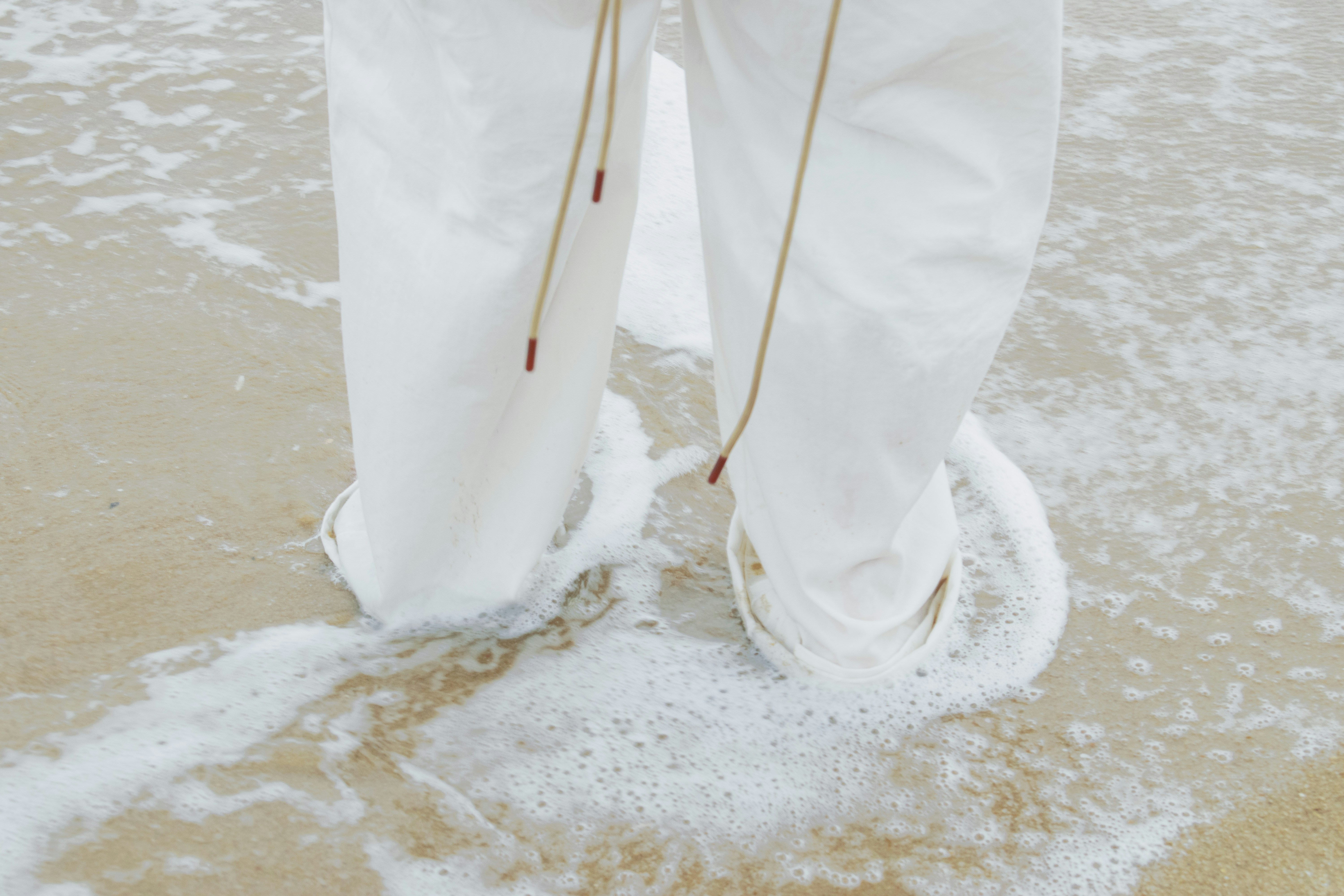 a person in white pants standing on a beach