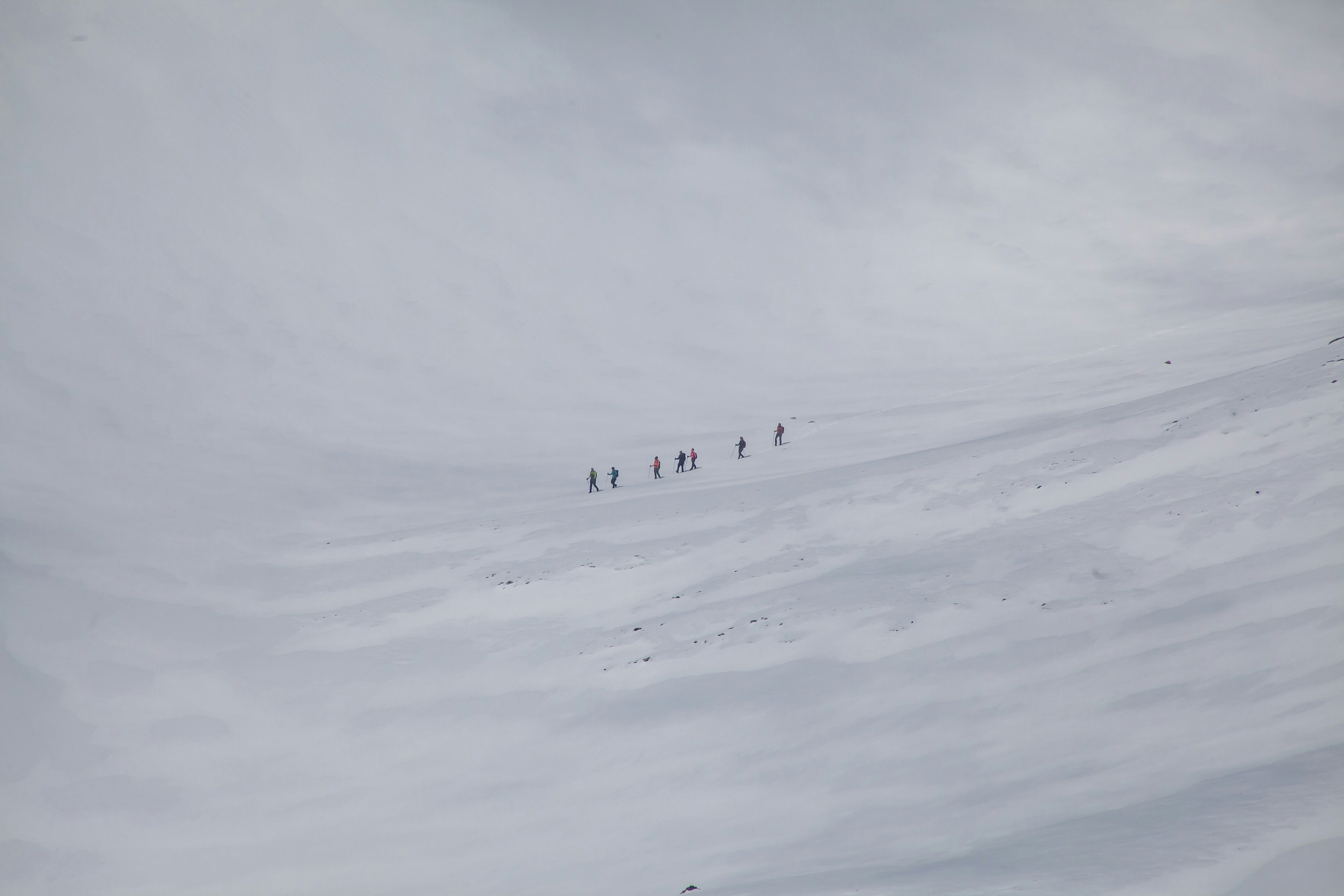 a group of people walking across a snow covered slope, 