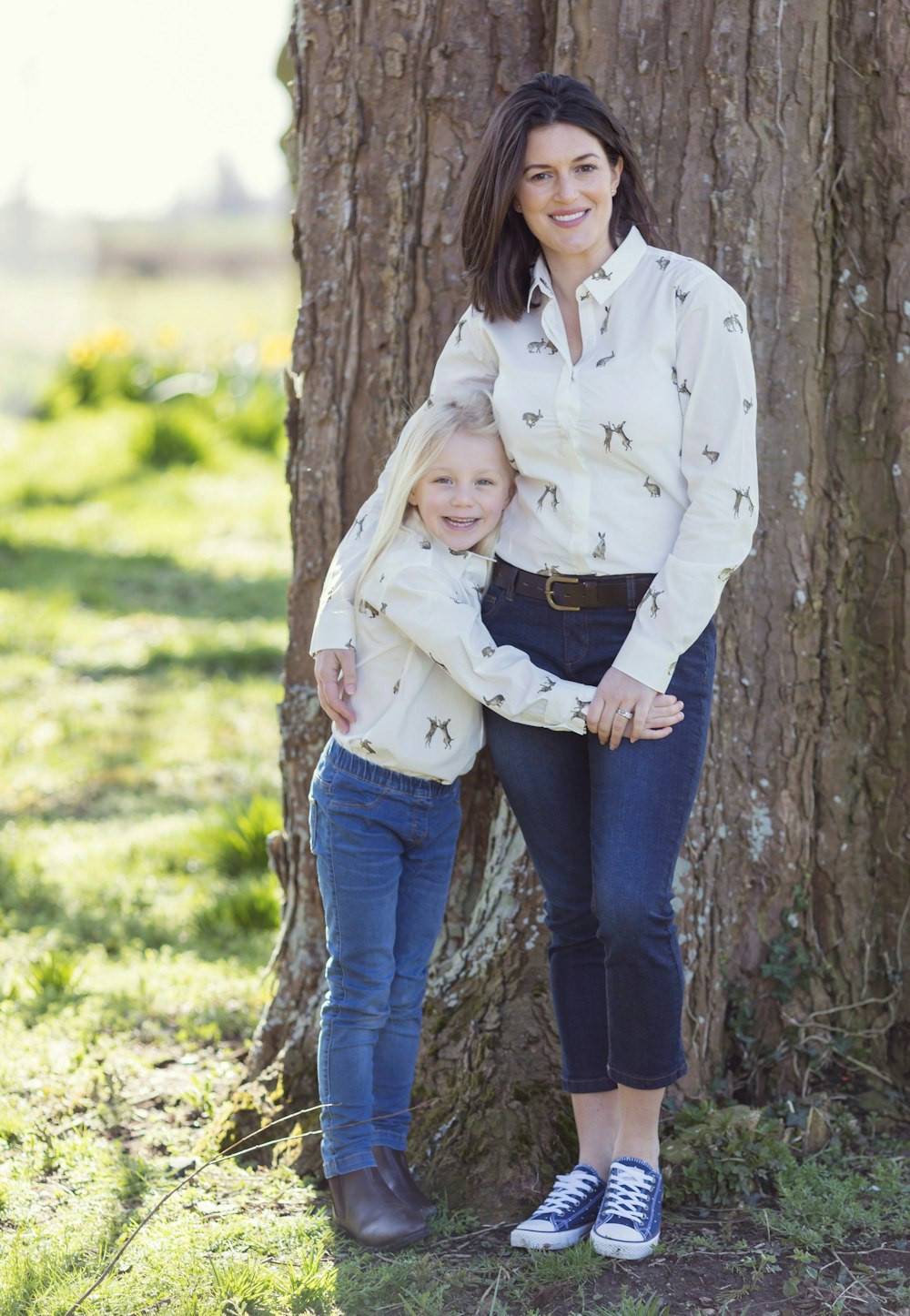 a woman and a child standing in front of a tree