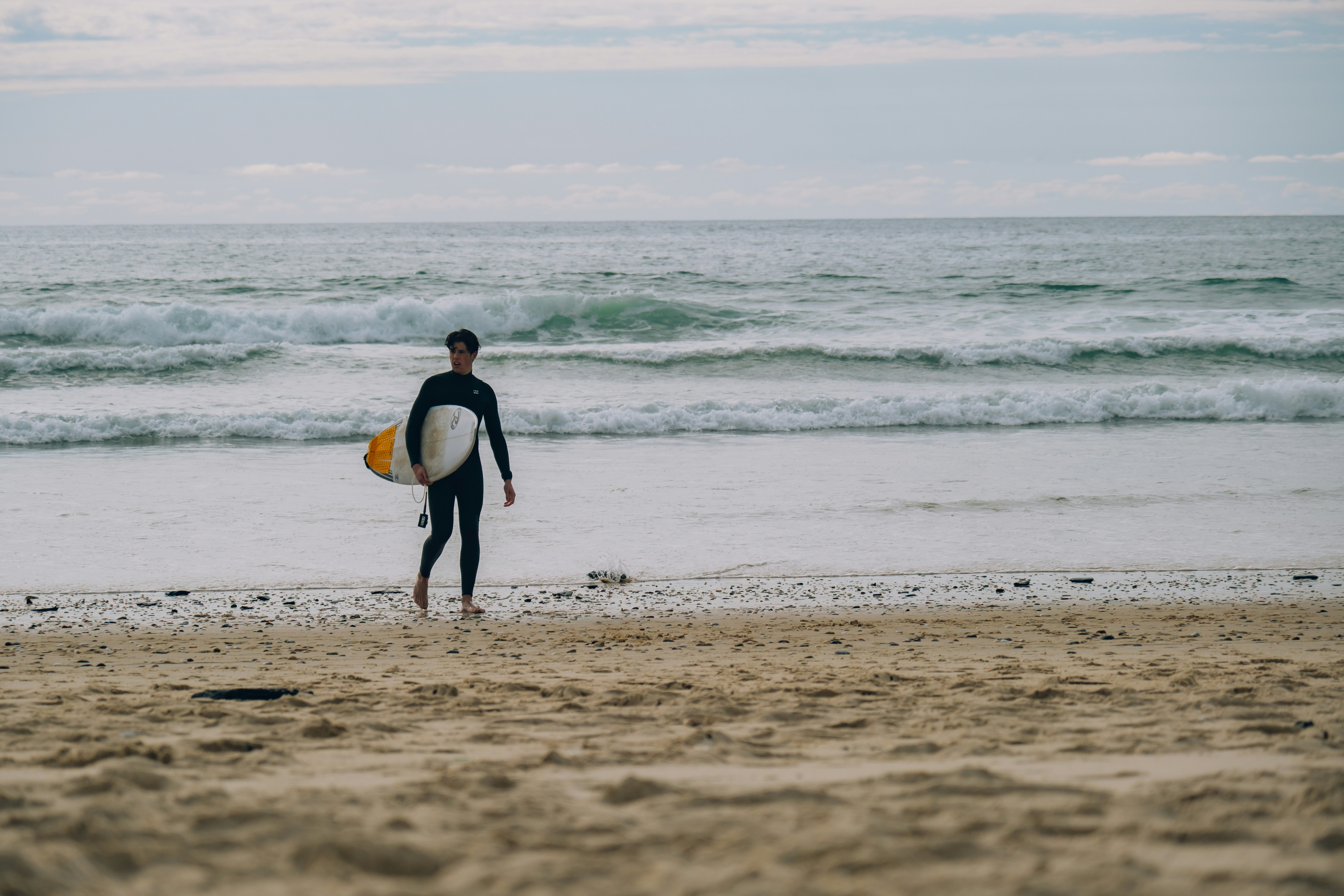 A man holding a surfboard on top of a sandy beach