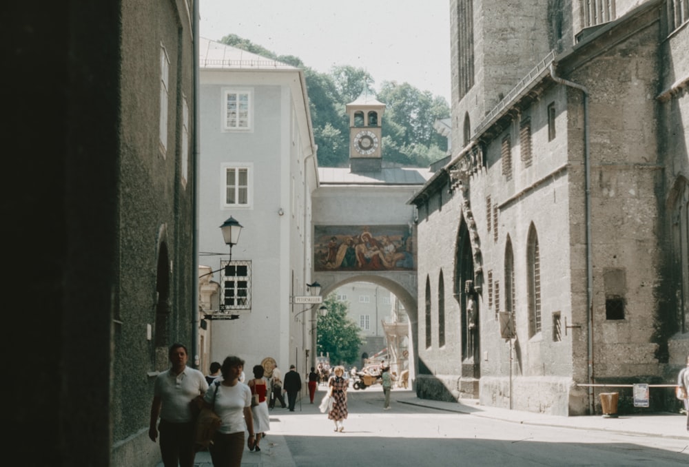 a group of people walking down a street next to tall buildings