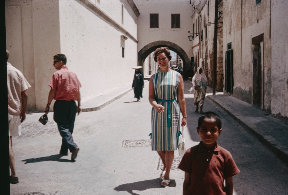 a woman walking down a street next to a little boy