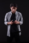 a man standing in a dark room looking at his cell phone