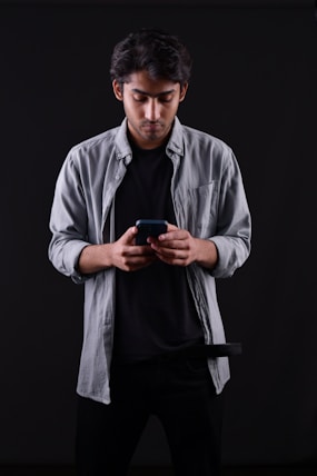 a man standing in a dark room looking at his cell phone