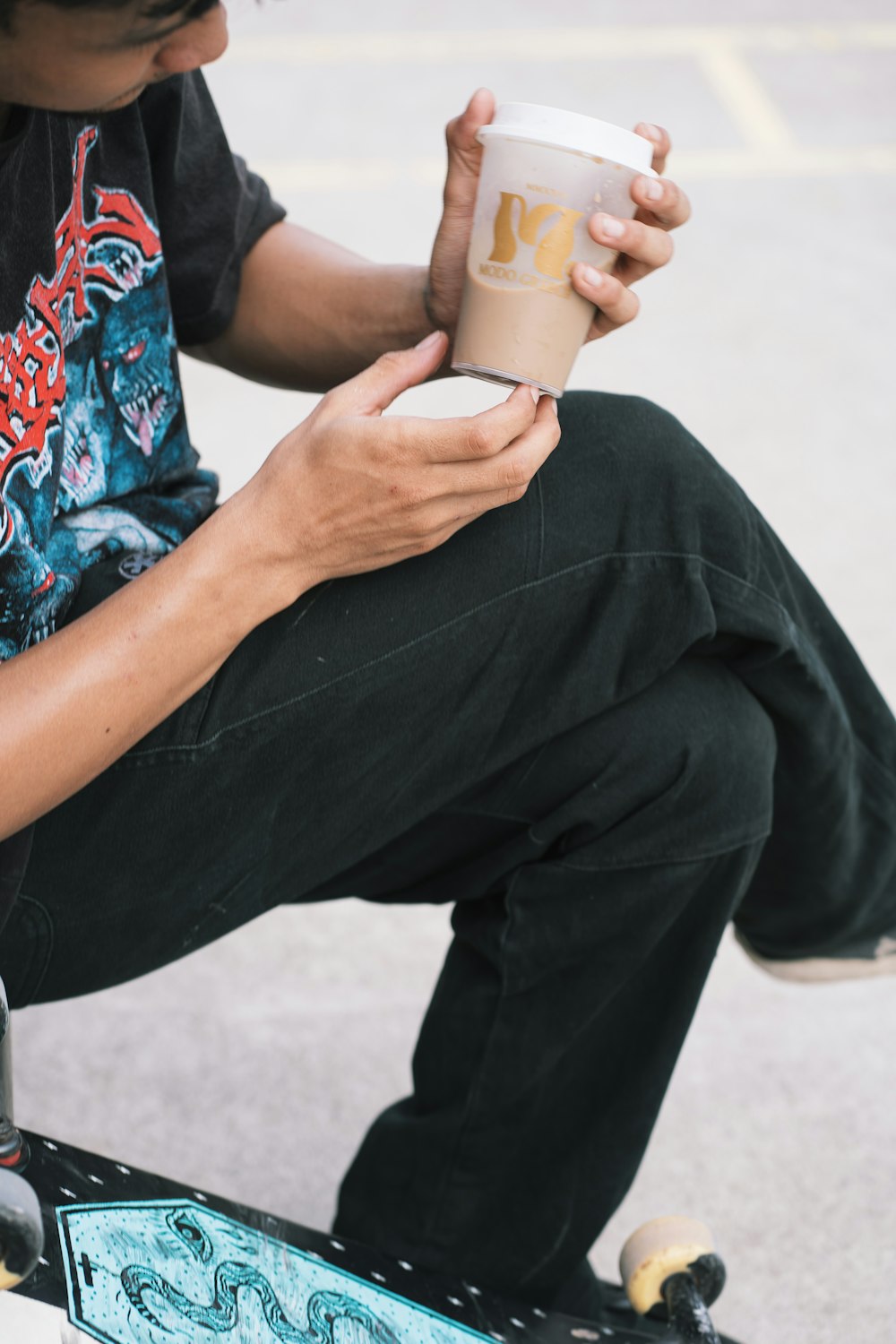 a man sitting on a skateboard holding a cup of coffee