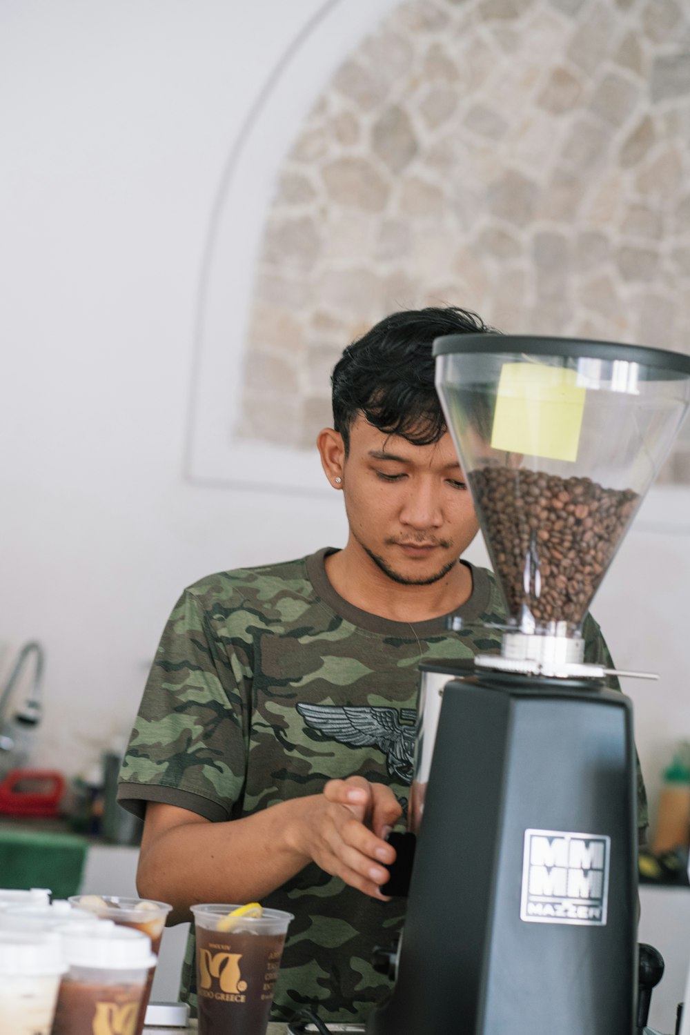a man in camouflage shirt using a coffee grinder