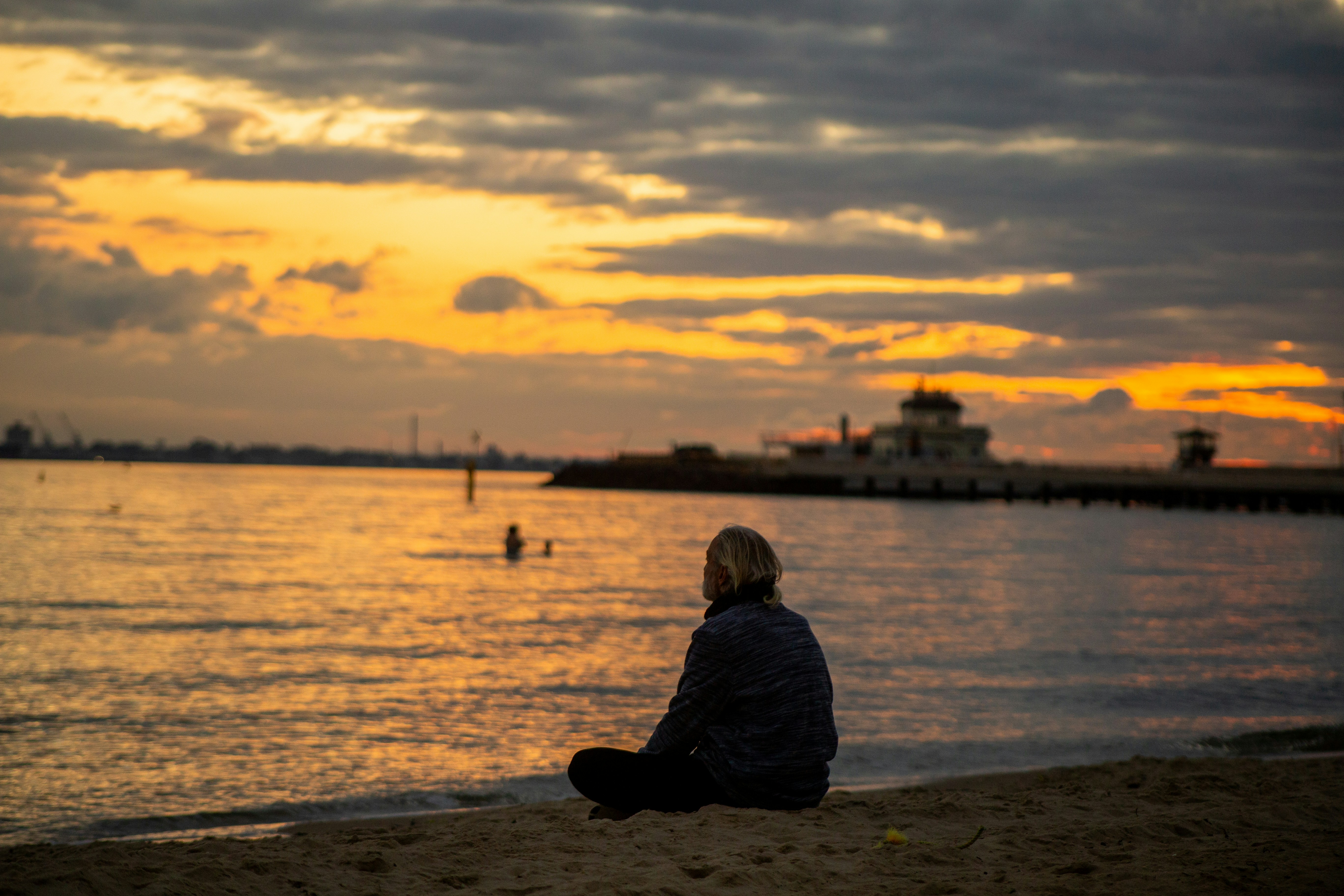 a person sitting on the beach watching the sunset